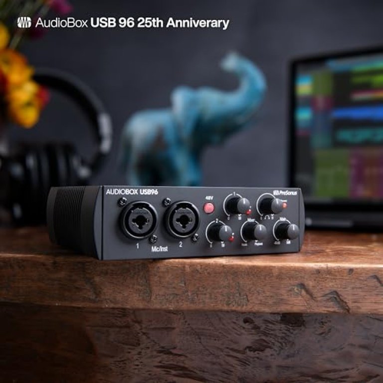 A PreSonus AudioBox USB audio interface on a wooden desk, with headphones and a computer in the background.